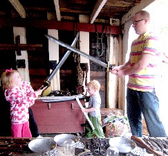 Dad and girl fake swordfighting while little kid wanders between them