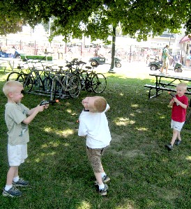 Three young boys aiming plastic pistols at each other