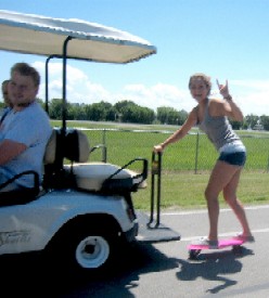 Girl on Skateboard Behind Golf Cart